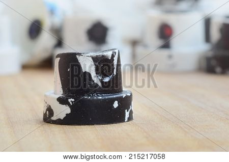 Several Plastic Nozzles From A Paint Sprayer That Lie On A Wooden Surface Against A Gray Wall Backgr