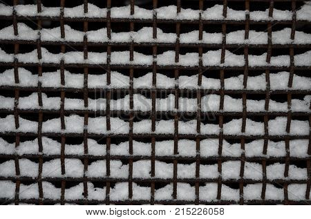 The metal mesh is covered with a layer of snow.