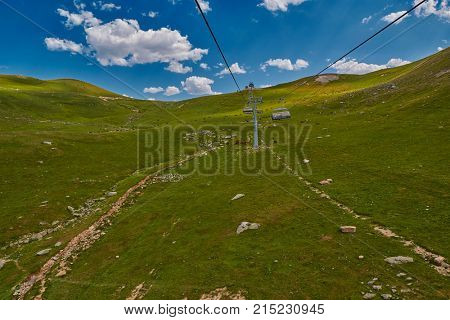 Aerial ropeway high in the mountains of Caucasus with grass plains and cow pastures in the background