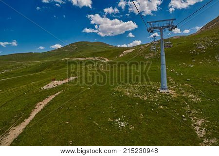 Aerial ropeway high in the mountains of Caucasus with grass plains and cow pastures in the background