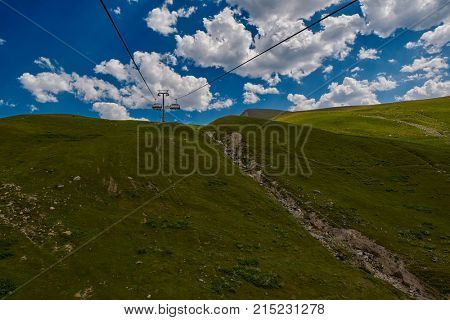Aerial ropeway high in the mountains of Caucasus with grass plains and cow pastures in the background