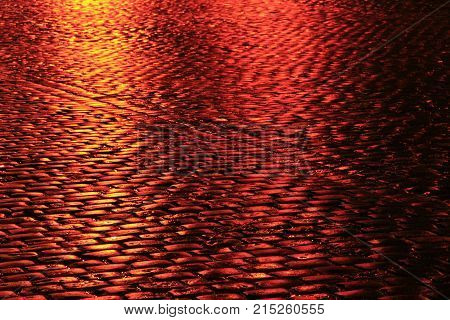 road with cobblestone pavement in the red lights of night city
