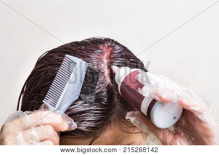 Woman Attempting To Apply Chemical Hair Color Onto Scalp