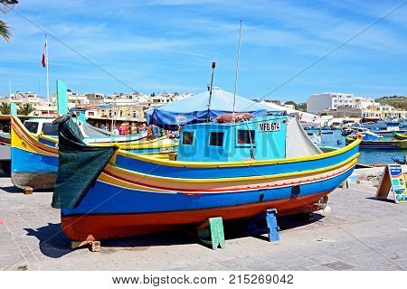 MARSAXLOKK, MALTA - APRIL 1, 2017 - Traditional Maltese Dghajsa fishing boats in the harbour with town buildings to the rear Marsaxlokk Malta Europe, April 1, 2017.