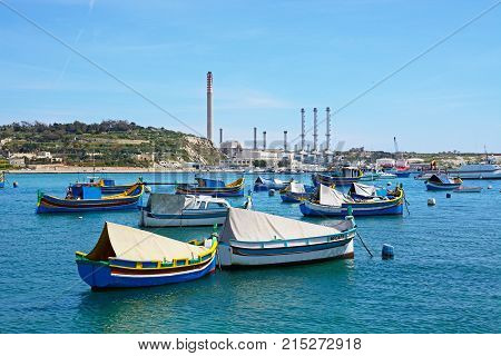 MARSAXLOKK, MALTA - APRIL 1, 2017 - Traditional Maltese Dghajsa fishing boats in the harbour with Delimara power station to the rear Marsaxlokk Malta Europe, April 1, 2017.