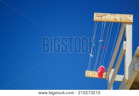 Colorful brightly clothespins and pink rag hanging on rope at the rescue station on background of blue sky Sironit beach Netanya Israel