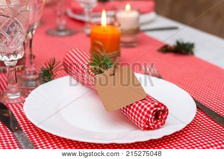 Festive composition with candles and plates. Table decoration. A beautiful table setting red table cloth tablecloth in the box. Christmas dinner. A Napkin decorated with inscription Merry Christmas.