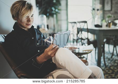 Smiling young woman wearing casual clothes and using electronic device while spending relax time in vacation travel.Attractive woman owner communicating on digital tablet.Blurred background
