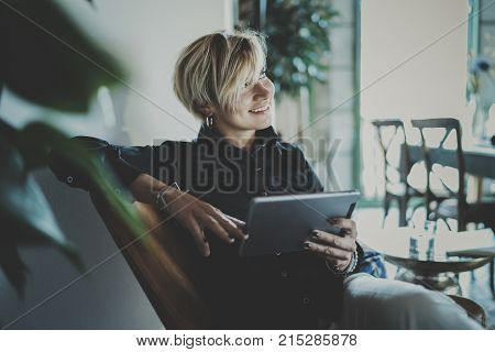 Smiling young woman wearing casual clothes and using electronic device while spending relax time in vacation travel.Attractive woman owner communicating on digital tablet.Blurred background