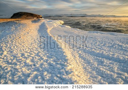 Ice floes floating on the fog water in the lake Baikal and hill, Russia. Sunset