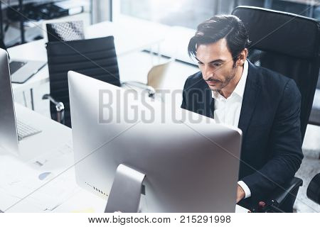 Elegant man using desktop computer at modern office.Panoramic windows on blurred background.Horizontal