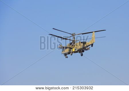 Green Helicopter Flies Against The Blue Sky