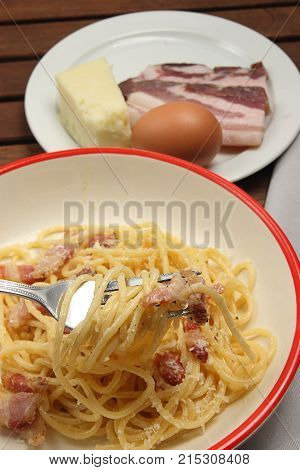 spaghetti carbonara into plate, with egg, chees and bacon