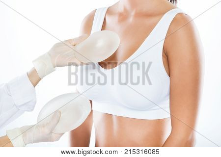 Female Doctor Choosing Mammary Prosthesis With Her Patient Over White Background.