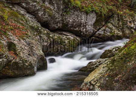 Water rushing through a narrow rocky corridor in a mountain landscape horizontal aspect