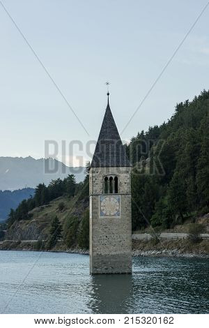 Church under water drowned village mountains landscape and peaks in background. Reschensee Lake Reschen Lago di Resia. Italy Europe Südtirol South Tyrol Upper Adige Alto Adige