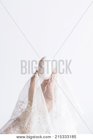 one egg in lace in hand on white background