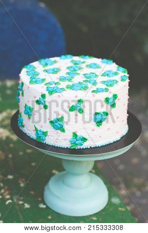 white cake with blue roses on a wooden table
