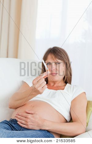 Gut aussehende schwangere Frau hält eine Zigarette beim liegen auf dem Sofa