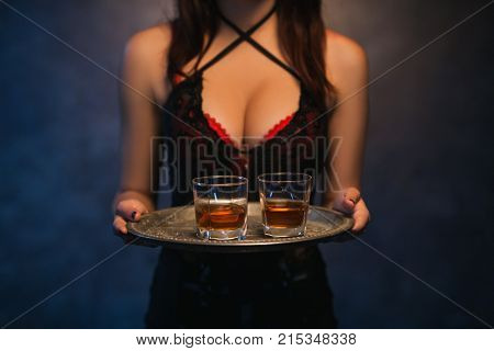 Sexy woman holding a tray of alcohol drinks. Bad habits. Immoral lifestyle. Elite night clubs for rich people concept