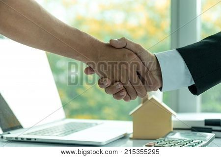 Estate Agent Sitting In A Desk Shaking Hands With Customers After Signing A Home Purchase Contract.