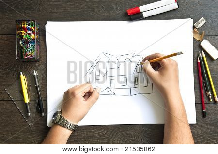 Mano escribiendo en una casa de plan