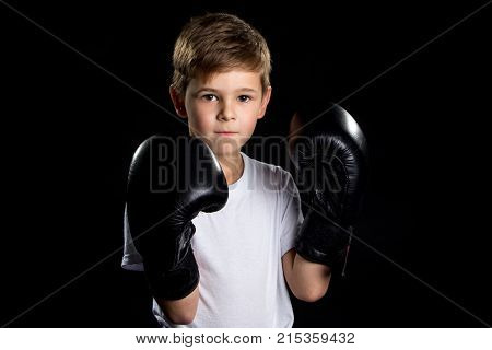Little boxer portrait in black boxing gloves in closed position.