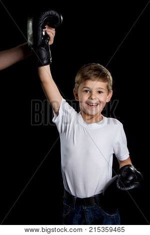 The little winner. Extremely happy little boxer with right hand up in black boxing gloves.