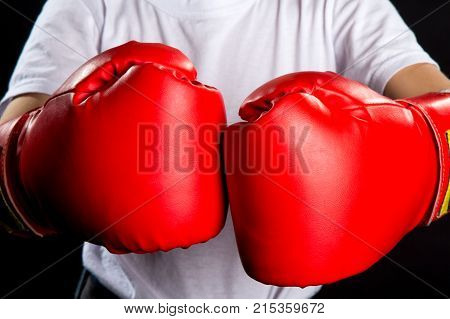 Red boxing gloves together in the front of the chest, macro.