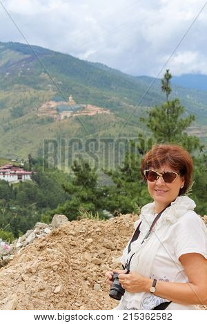 Beautiful Caucasian woman in white smiling to the camera with a view of giant Buddha Dordenma statue on the background Bhutan Asia.