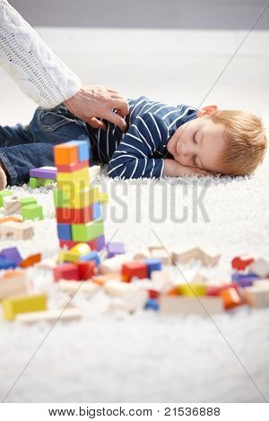 Sladký chlapeček unavená v hraní, položila na podlahu, mezi kostkami.?