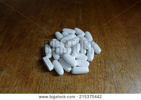 Batch Of Calcium Citrate Tablets On Wooden Table