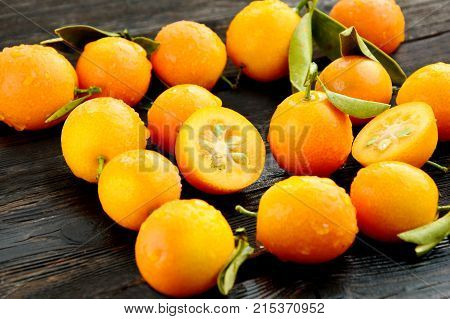 Kumquats or cumquats with water drop and shadow on wet wooden floor