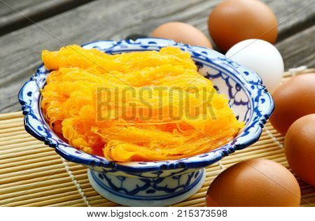Golden egg strip is Thai desserts made from eggs with Thai style bowl on wooden background