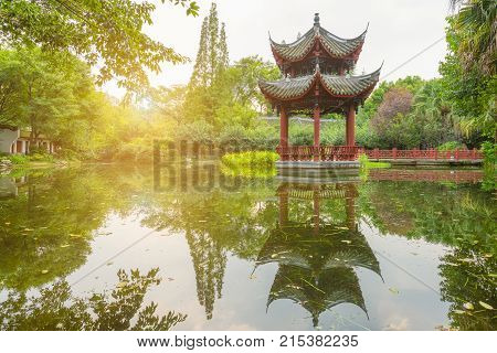 Chinese pavilion reflecting in a pond in BaiHuaTan public park, Chengdu, China