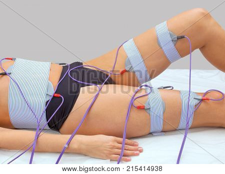 The procedure of myostimulation on the legs and buttocks of a woman in a beauty salon. Caring for the body reducing excess weight.