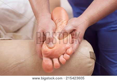 The doctor-podiatrist does an examination and massage of the patient's foot in the clinic.
