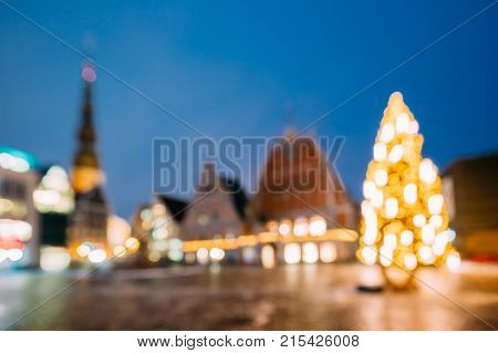 Riga, Latvia. New Year Boke Lights Xmas Christmas Tree Decoration And Festive Illumination Of Town Hall Square. Defocused Blue Bokeh Background Effect. Design Backdrop.