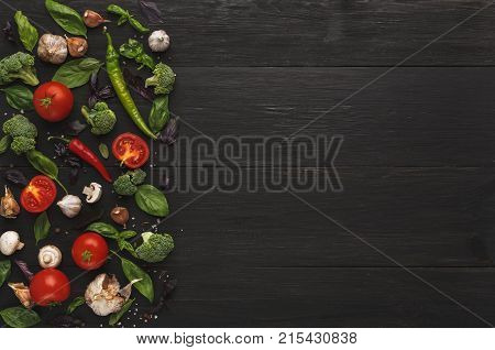 Border of fresh vegetables on wooden background. Healthy natural food on rustic wooden table. Sliced tomatoes, garlic, mushroom, broccoli, chilli, bazil and herbs, top view