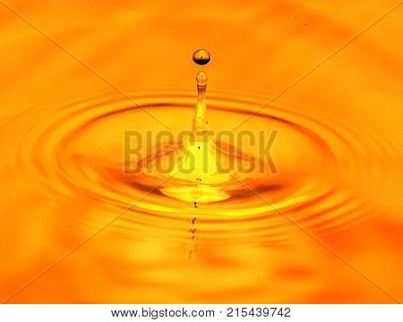 a drop of water falls in a golden water. macro .