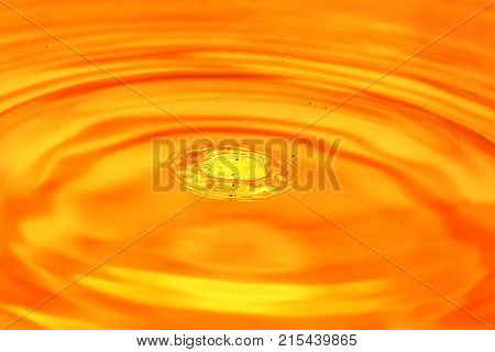 a drop of water falls in a golden water. macro .