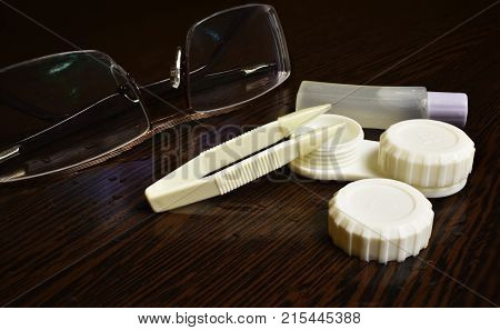 glasses tweezers lens case and solution on the table