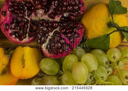 fruit ripe red pomegranate white grapes orange mandarin with green leaves and persimmon