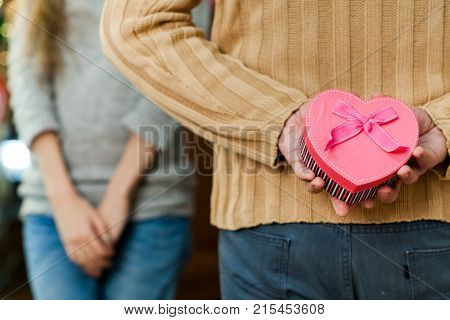 couple in love celebrate valentine's day. Man making surprise on holiday to his pretty wife. Wife close her eyes and waiting for present. Concept of happy valentine's day