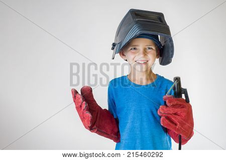 Happy little kid in welder mask and welding equipment. Welding equipment welding mask protective leather gloves welding electrodes. Fun concept. Child dreaming of future profession. Career choice.