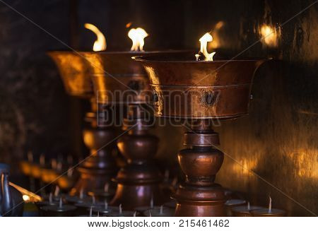 Big oil lamps burn in the Buddhist temple as fire gift from pilgrims.
