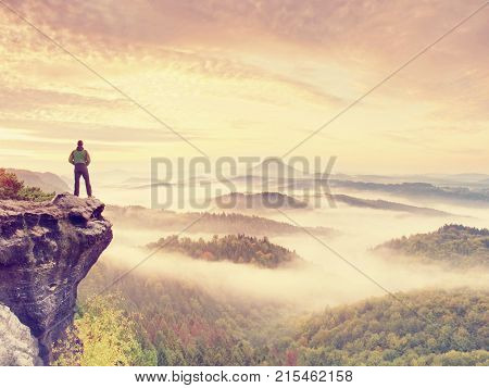 Man Stay On Rocky Peak Within Daybreak And Watch Over Misty Landscape.