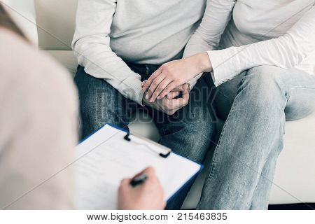 We are strong. Two people holding hands and sitting close to each other while consulting with their doctor