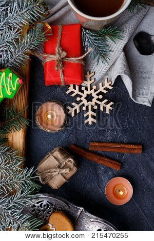 New Year's concept, top view, on the table of cinnamon sticks, coffee, gift boxes, round small candles, snowflake, all this on a black background.