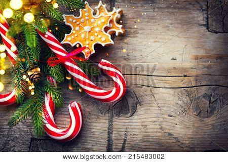 Christmas Holiday Background with various Gingerbread cookies, Candy Cane and evergreens border over wooden table. Christmas and New year food. Christmas decoration and sweets on wood background